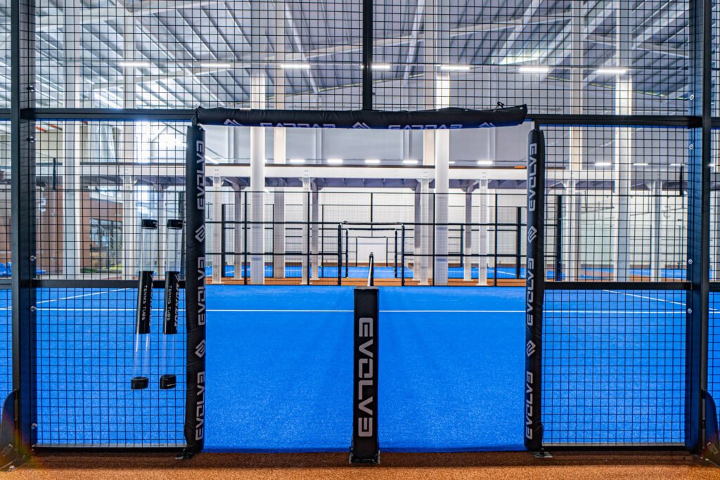 Evolve padel court with blue turf and glass walls inside a sports hall